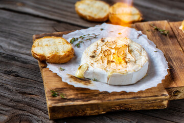 Traditional French homemade baked Camembert cheese with thyme and baguette bread. Gourmet traditional Breakfast close up