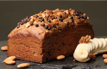 Homemade banana bread with walnut, almonds on a stone background.