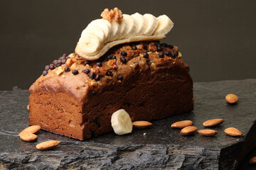 Homemade banana bread with walnut, almonds on a stone background.