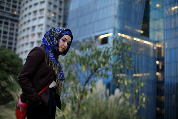 Medium shot pictures of beautiful model using hijab with office buildings in the back