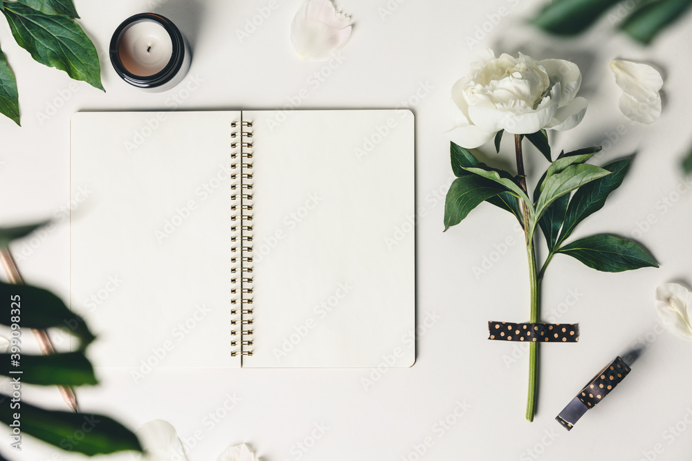 Wall mural flat-lay of beautiful peony flower taped on white background and open notebook
