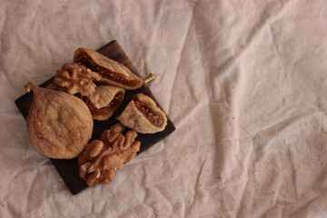 Close up dried figs and walnuts on the brown plate and brown healthy food background. Top view dried fruit and nut are healthy desert for human health. space for text.