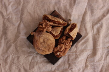 top view walnuts and dried figs are healthy food for diet, closeup. Dried fruit and nuts on the wooden plate for healthy food background, space for text.