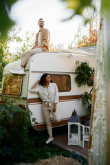 Happy couple poses near rv, camping in a trailer