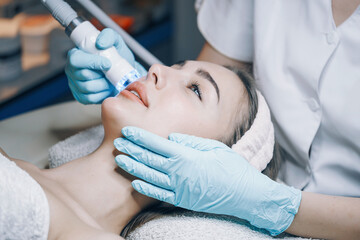 doctor performs cosmetic procedures in a beauty salon on the face of a young woman