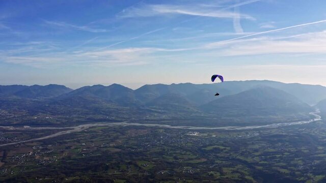 colorful paraglider in air with Piave river in background, adventure sport