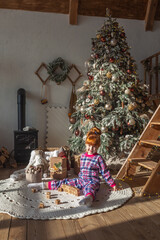 happy little girl playing near christmas tree at home, winter holidays, real people