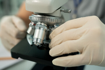 Gloved hand of contemporary worker of scientific laboratory fixing metallic lens