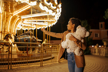 Woman with soft toy near the carousel in park © Nomad_Soul