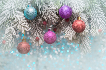 Christmas balls on frosty fir-tree branches over holiday background
