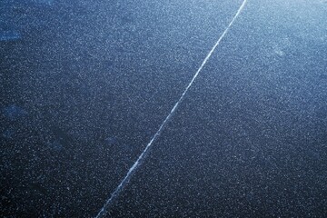 Fototapeta premium Abstract texture of dark ice with snow crystals and white line on the surface. Frozen river
