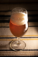 A glass of delicious craft beer on an authentic table cloth.