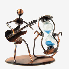 Hourglass in a metal case and blue sand. Next to the figure of a man with a guitar. Isolated on a white background. Close up