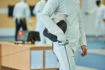 body parts of the athlete fencing in a suit uniform with a sword and mask. An active Olympic sport.