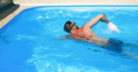 A young man trains in a home pool. Athlete swims in countercurrent. Fitness training as a healthy...
