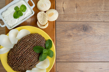 raw quibe with sliced onion, dried curd, pita bread and mint leaves