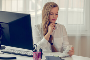 Business woman in formal wear, sitting at her work place in a light office