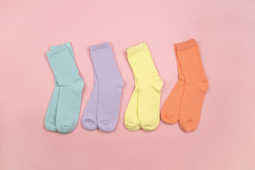 Colored children's socks without a pattern, pink, lilac, yellow, orange on a pink background with a place for text, copy space, flatly, minimal style. Concept for children's clothing, housekeeping