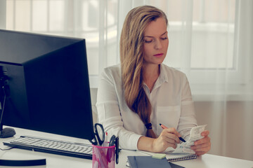 Business woman in formal wear, sitting at her work place in a light office