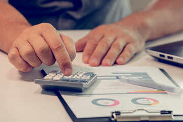 Close up of businessman hands working with finances using calculator on white desk in the office.