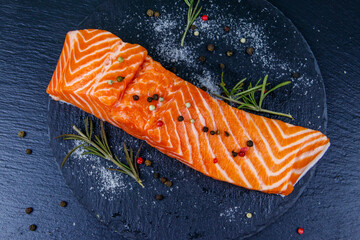 Raw salmon fillet with spices on black slate. Top view