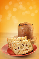 Delicious slice of Panettone with candied fruit on the table on a blurred background.