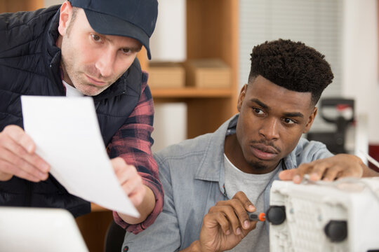workmen follow instructions for the assembly of an electrical appliance