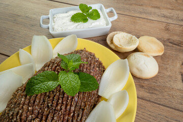 raw quibe with sliced onion, dried curd, pita bread and mint leaves