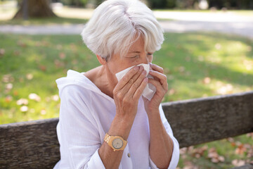senior woman has a runny nose having flowers pollen allergy - obrazy, fototapety, plakaty