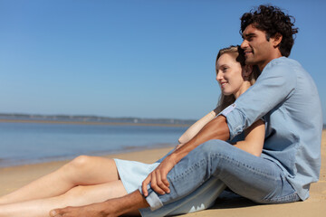 Naklejka na ściany i meble pretty young couple sitting on the beach