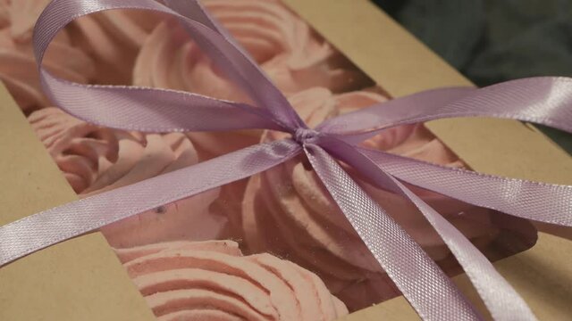 Gift box with a bow of ribbons with berry currant marshmallows. Rotation. Close-up.
