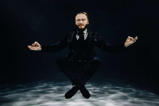 A Man In A Strict Suit Under Water In The Lotus Position