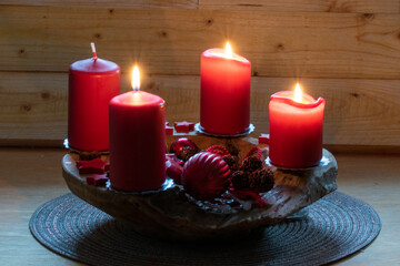 Rote brennende Kerzen auf einem Adventsgesteck. Es ist der dritte Advent. Bald ist Weihnachten.