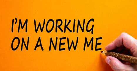 New me symbol. Hand writing 'i am working on a new me', isolated on orange background. Business and new me concept, copy space.