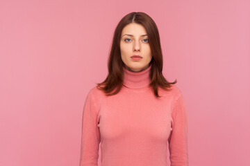 Portrait of serious self assured brunette woman looking at camera with confidence, sensuality and...