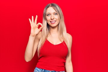 Young blonde woman wearing casual clothes smiling positive doing ok sign with hand and fingers. successful expression.