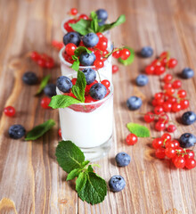Healthy breakfast - yogurt with fresh berries in glass jar, on wooden background