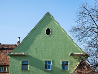 Fototapeta na wymiar Green painted facade of an old house in the medieval town of Sighisoara, Romania