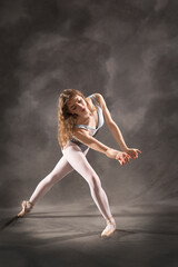 Obraz na płótnie Canvas Young adult ballerina in the studio, dancing in gray leotard.