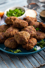 Minced meatball in dish with spices and parsley on wooden background. 