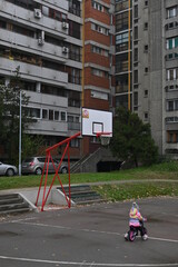 Child riding a mini bicycle on a basketball court in blocks of the city of Belgrade