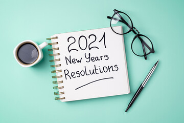 New year 2021 goals on desk. 2021 goals with open notebook, coffee cup, eyeglasses, plant succulent...