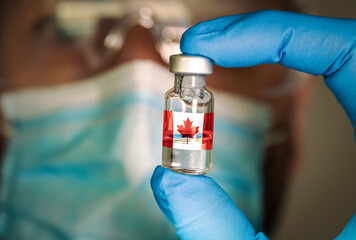 Close-up of medical vial with the flag of Canada and a blurred doctor on the background. Selective...