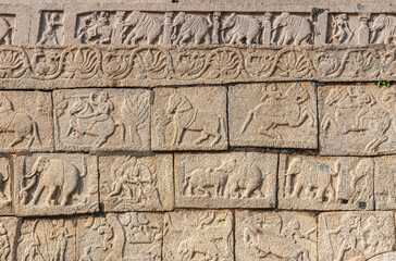 Hampi, Karnataka, India - November 4, 2013: Part of base of Mahanavami Dibba or the Dussehra Platform. All around brown stone mural sculptures. Closeup of 5 rows.