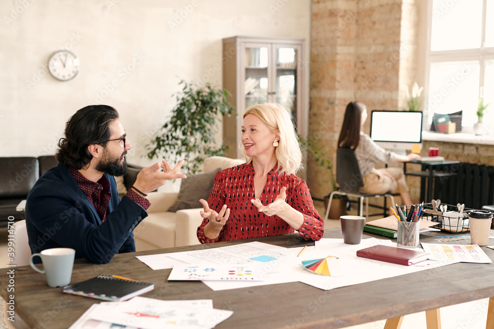 Canvas Prints Young bearded designer and his happy mature female colleague brainstorming