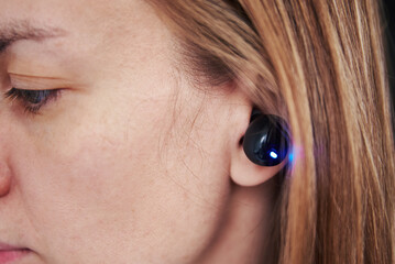 Woman listening music through wireless earphones. Caucasian woman using bluetooth headhones in the...