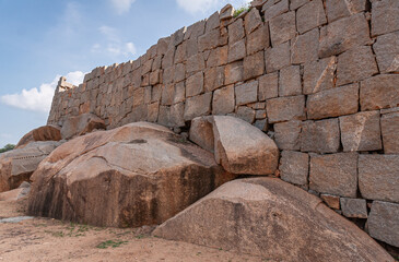 Hampi, Karnataka, India - November 4, 2013: Royal Enclosure. Part of the surrounding wall with boulders as reinforcements in front under light blue sky.