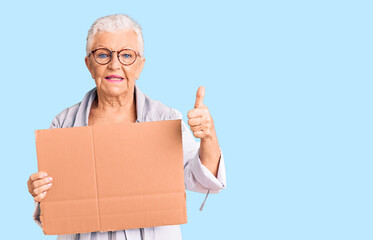 Senior beautiful woman with blue eyes and grey hair holding we need a change banner smiling happy and positive, thumb up doing excellent and approval sign