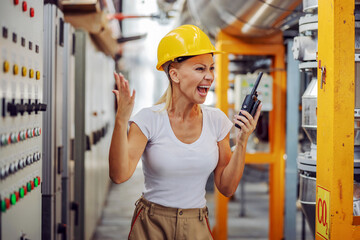 Angry hardworking female supervisor in working suit with protective helmet on head yelling over...