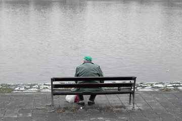 Homeless man sitting on a bench and looking at the Danube river. Emotional. 